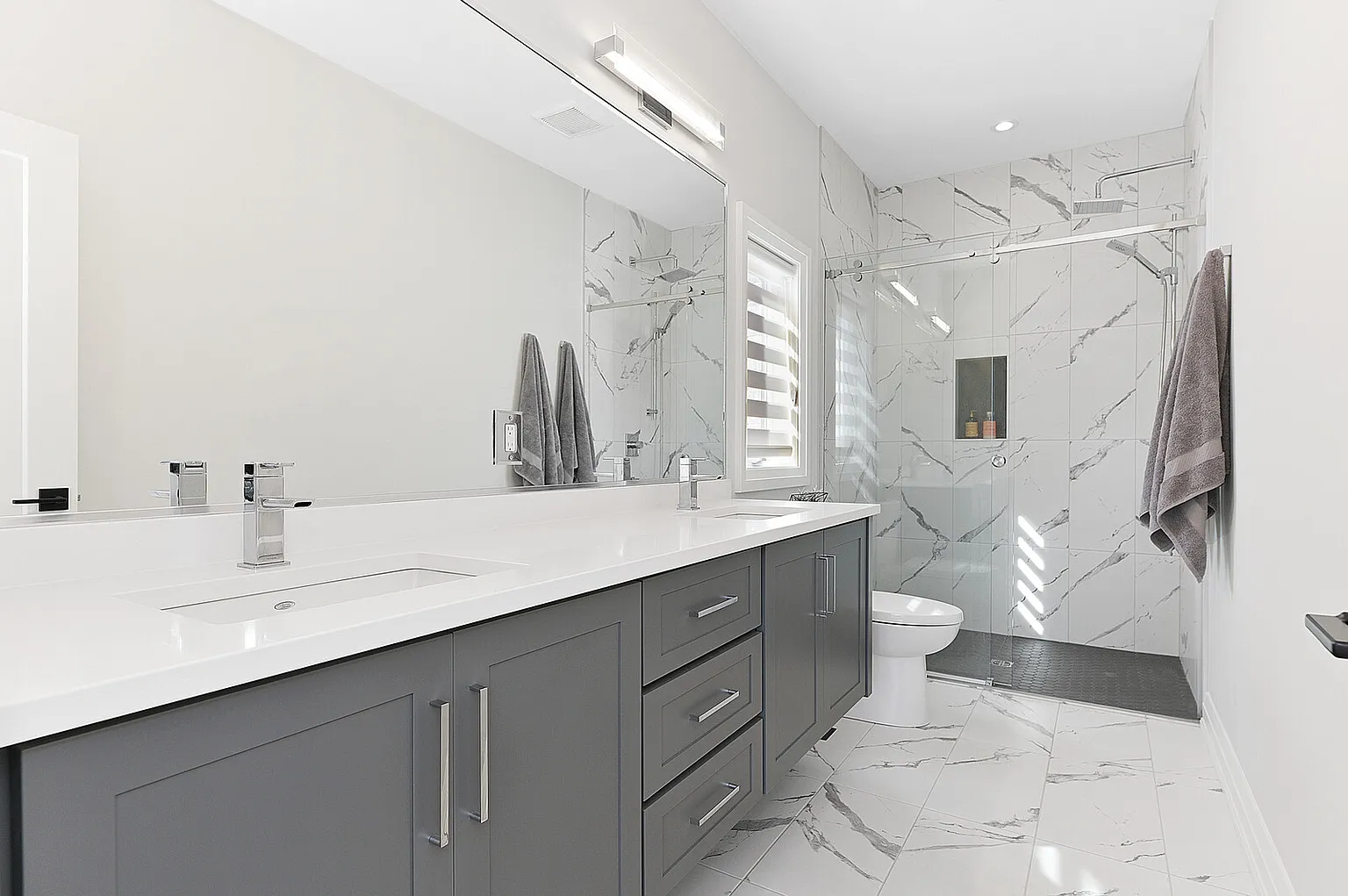 Bathroom with marble-look tile shower and double vanity