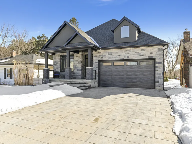 Custom craftsman bungalow exterior with stone facade and paver driveway